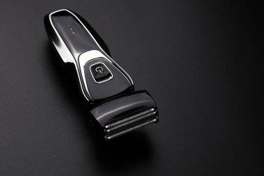 Siyah erkek elektrikli tıraş makinesi, siyah arka planda izole edilmiş.