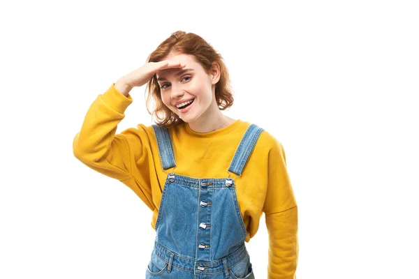 红头发的年轻女子穿着黄色休闲装 遥望远方 手挽手与白色背景隔离 搜索概念 — 图库照片