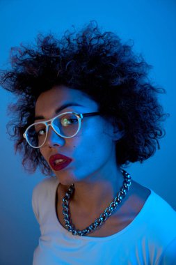 Stüdyonun arka planında izole edilmiş neon ışıklı bukleli havalı Kazak model kız portresi.