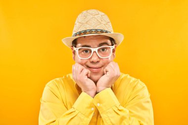 Sarı arka planda izole edilmiş, şapkalı, gülümseyen şişman bir adamın portresi. Seyahat konsepti.