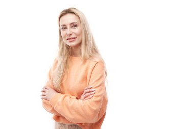 Portakal rengi poz veren çekici sarışın kız portresi ve beyaz stüdyo arka planında neşeli bir şekilde izole edilmiş gülümseme.