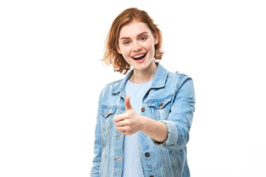 Genç kızıl saçlı kadın elini kaldırıyor ve beyaz arka planda izole kameraya gülümsüyor.