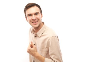 Genç esmer adam elini kaldırır ve beyaz arka planda izole edilmiş kameraya gülümser.