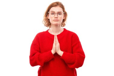 Genç kızıl saçlı kadının portresi beyaz arka planda izole edilmiş dua hareketleriyle ellerini kavuşturdu. Huzurlu, müteşekkir, güvenilir, bir dilek konsepti