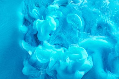 Blue abstract ocean background. Splashes and waves of paint under water, clouds of smoke in motion.