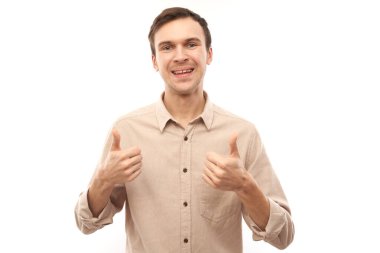 Genç esmer adam elini kaldırır ve beyaz arka planda izole edilmiş kameraya gülümser.