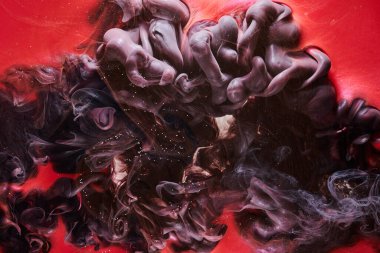 Red black abstract ocean background. Splashes and waves of paint under water, clouds of smoke in motion