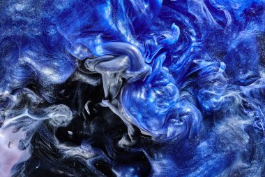 Koyu mavi soyut okyanus arka planı. Sıçramalar, damlalar ve dalgalar suyun altında parlayan boya bulutları hareket halindeki duman bulutları.