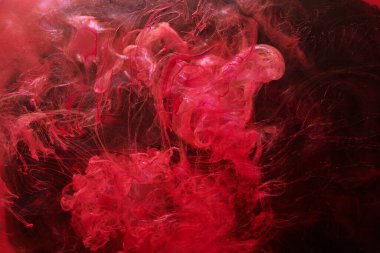 Red abstract ocean background. Splashes and waves of paint under water, clouds of smoke in motion.