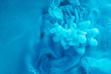 Blue abstract ocean background. Splashes and waves of paint under water, clouds of smoke in motion.