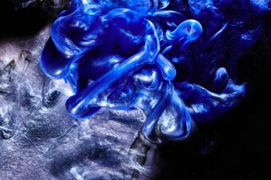 Koyu mavi soyut okyanus arka planı. Sıçramalar, damlalar ve dalgalar suyun altında parlayan boya bulutları hareket halindeki duman bulutları.