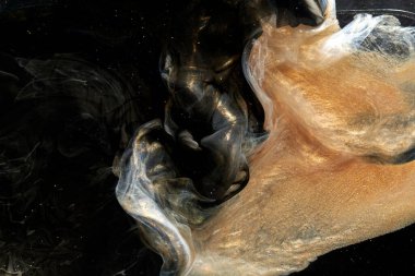Black gold abstract ocean background. Splashes and waves of sparkling paint under water, clouds of interstellar smoke in motion
