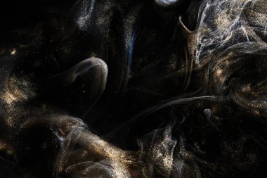 Black gold abstract ocean background. Splashes and waves of sparkling paint under water, clouds of interstellar smoke in motion