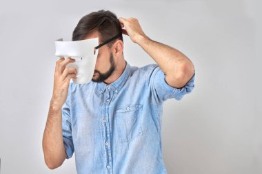 Yüzünde beyaz maskeli gizemli adam stüdyo arka planında izole edilmiş.