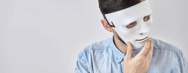 Mystery man in white mask on his face isolated on studio background