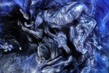 Koyu mavi soyut okyanus arka planı. Sıçramalar, damlalar ve dalgalar suyun altında parlayan boya bulutları hareket halindeki duman bulutları.