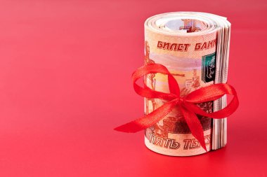 Rus Rublesi, beş bin banknot, kırmızı arka planda kırmızı kurdeleli bir tomar para, hediye konsepti.