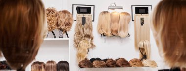 Güzellik salonundaki metal peruk tutuculara sabitlenmiş farklı renklerde doğal görünümlü peruklar. Bir sıra manken kafası ve farklı peruklu saçlar.