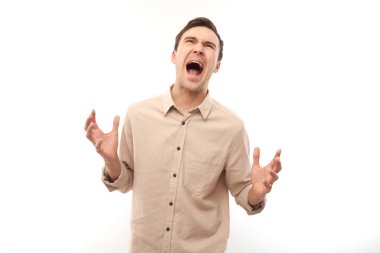 Portre kızgın esmer genç erkek çığlık beyaz stüdyo arka planda izole, olumsuz duygular gösteren