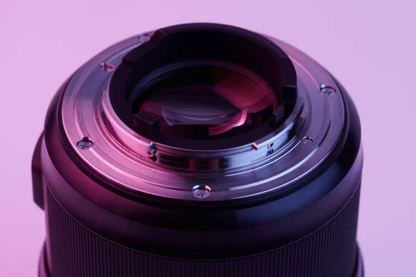 粉红淡紫色霓虹灯下白色背景上的相机镜头特写 — 图库照片