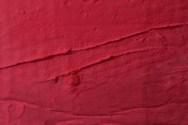 Dekoratif kırmızı macun arka planı. Spatula ile doldurulmuş duvar dokusu, alçı üzerine kaotik çizgiler ve darbeler. Yaratıcı tasarım, taş desen, cemen