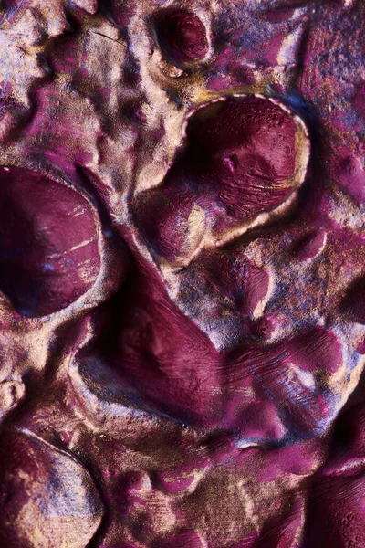 Decorative purple gold putty background. Wall texture with filler paste applied with spatula, chaotic dashes and strokes over plaster. Creative design, stone pattern, cemen