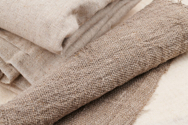 Linen in different textures and colors. Natural fabrics from organic flax and cotton in rolls, homespun textile handmade. Burlap and canvas for eco, rustic, boho, hygge decor