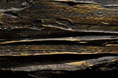 Dekoratif siyah altın macun arka planı. Spatula ile doldurulmuş duvar dokusu, alçı üzerine kaotik çizgiler ve darbeler. Yaratıcı tasarım, taş desen, cemen