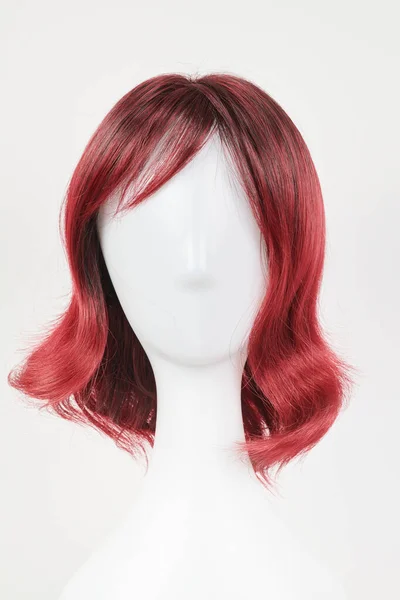 白いマネキンの頭部の自然な一見赤いウィッグ 白地に隔離されたプラスチック製のウィッグホルダーの中丈の髪 フロントビュー — ストック写真