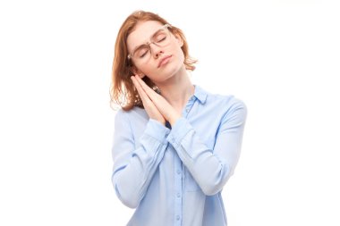 Stüdyo portresi genç kızıl saçlı kadın avuçlarını kafasının altına koyup beyaz arka planda yalnız uyuyormuş gibi yaptı.