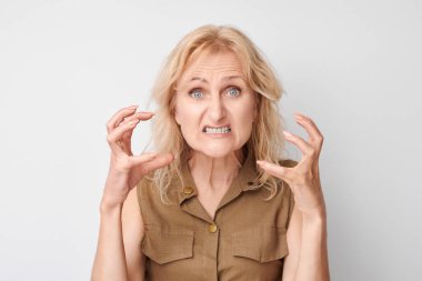 Beyaz stüdyo arka planında izole edilmiş birini bağırıp boğuyormuş gibi yapan öfkeli olgun kadın portresi.