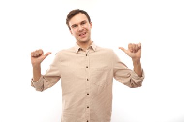 Esmer erkek portresi gülümseyen, kendinden emin görünen, kendini beyaz arka planda izole edilmiş parmaklarla gösteren. Kendini seçer, kendine güven kavramı.