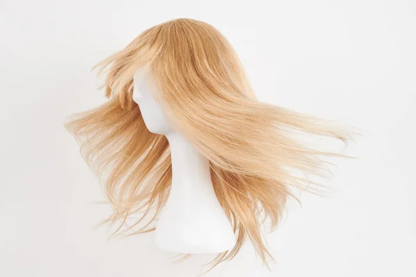 自然的金发碧眼的假发戴在白色的模特头上 塑料假发支架上的长发被白色背景隔离 侧面竞争 — 图库照片