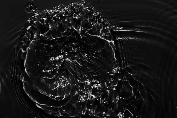 Water black surface abstract background. Waves and ripples texture of cosmetic aqua moisturizer with bubble