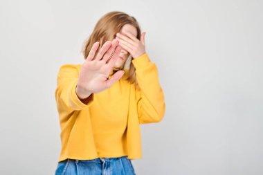 Yüzü avuçlarında hayal kırıklığına uğramış öğrenci portresi beyaz stüdyo arka planında elleri izole bir şekilde dur işareti yapıyor.