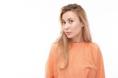 Beyaz stüdyo arka planında izole edilmiş şüpheli bir şekilde kameraya bakan genç sarışın kızın portresi şüpheci bir şekilde şaşı bakıyor.