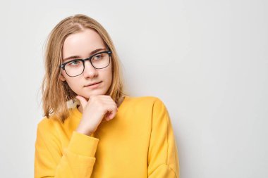 Gözlüklü zeki sarışın kız çenesine dokunuyor, beyaz stüdyo arka planında fotokopi çekmeyi seçiyor. Kendine güvenen zeki dahi.