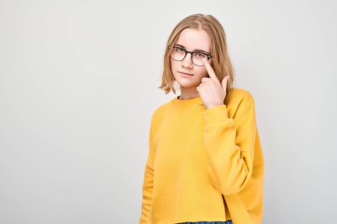 Genç bir kızın portresi beyaz stüdyo arka planında izole edilmiş gözlüklerine işaret ediyor. Görüş kontrolü ve görme kaybı konsepti, gözlük dükkanı