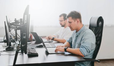 Çeşitli ofislerde bilgisayar üzerinde çalışan iki profesyonel erkek programcının portresi. Modern bilişim teknolojileri, yapay zekanın geliştirilmesi, programlar, uygulamalar ve video oyunları konsepti
