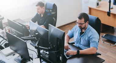 Çeşitli ofislerde bilgisayar üzerinde çalışan iki profesyonel erkek programcının portresi. Modern bilişim teknolojileri, yapay zekanın geliştirilmesi, programlar, uygulamalar ve video oyunları konsepti