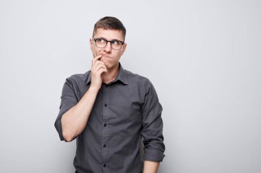 Çeneye dokunan tişörtlü zeki bir adamın portresi şüphelerin beyaz stüdyo arka planında kopya alanı ile izole edildiğini düşünüyor.