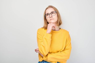 Gözlüklü zeki sarışın kız çenesine dokunuyor, beyaz stüdyo arka planında fotokopi çekmeyi seçiyor. Kendine güvenen zeki dahi.