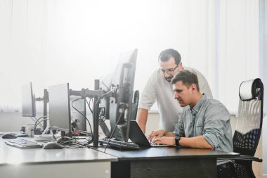 Çeşitli ofislerde bilgisayar üzerinde çalışan iki profesyonel erkek programcının portresi. Modern bilişim teknolojileri, yapay zekanın geliştirilmesi, programlar, uygulamalar ve video oyunları konsepti