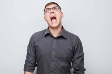 Beyaz stüdyo arka planında izole bir şekilde bağıran öfkeli genç adamın portresi. Şeytan patron suratı. İnsani duygular, yüz ifadesi kavramı