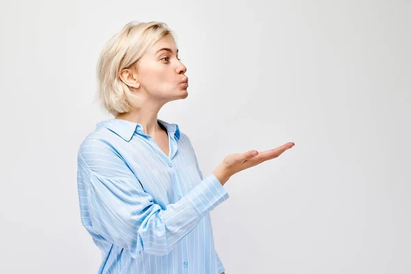 Portret Młodej Blondynki Wysyłającej Pocałunek Powietrza Trzymającej Coś Dłoni Demonstrującej — Zdjęcie stockowe
