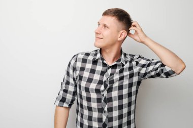 Kafasına dokunan tişörtlü zeki bir adamın portresi şüphenin beyaz stüdyo arka planında kopya alanı ile izole edilmiş seçimler olduğunu düşünüyor.