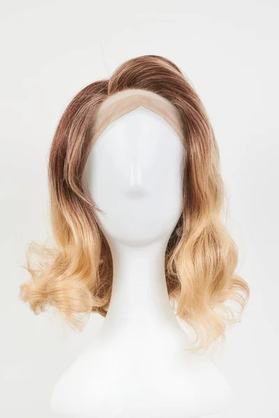 天然的金发碧眼的假发戴在白色的人体模特头上 在白色背景下隔离的塑料假发托架上剪下中等长度的头发 — 图库照片
