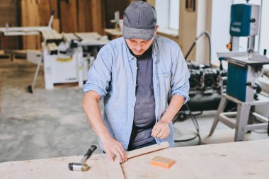 Marangoz marangozluk atölyesinde ahşapla çalışır. Adam profesyonel olarak ahşap işi yapıyor.