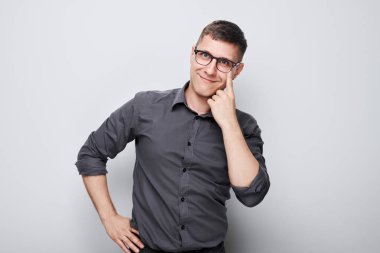 Genç erkek portresi beyaz stüdyo arka planında izole edilmiş gözlüklere işaret ediyor. Görüş kontrolü ve görüş kaybı, arama konsepti, gözlük sho