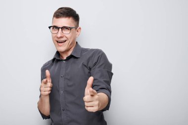 Kendine güvenen bir adamın portresi beyaz stüdyo arka planında izole edilmiş kamerayı işaret eder. Hoş geldin jesti, takımımıza katıl.